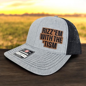 May include: A gray and black trucker hat with a brown leather patch that says "Rizz 'em with the 'Tism".