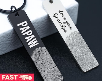 May include: Two rectangular keychains. One is black with the word "PAPAW" in white. The other is white with the words "Love you, grandpa" in cursive. Both keychains feature a fingerprint design at the bottom.