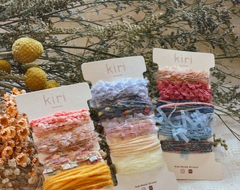 Puede incluir: Tres carretes de hilo de colores con el texto "kiri made studio" en cada etiqueta. El hilo es una mezcla de texturas, incluyendo esponjoso, peludo y brillante.