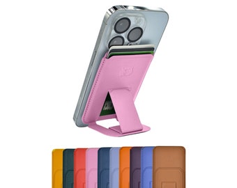 May include: A pink phone stand with a built-in card holder. The stand is made of a soft, flexible material and can be used to prop up a phone in landscape or portrait mode. The stand is also compatible with most phone cases. The image shows the stand in a variety of colors, including black, blue, brown, green, orange, pink, purple, red, and yellow.