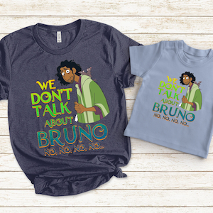 May include: Two t-shirts featuring a cartoon character and the text "We don't talk about Bruno. No, no, no, no..." printed on them. The larger shirt is navy blue and the smaller shirt is light blue.