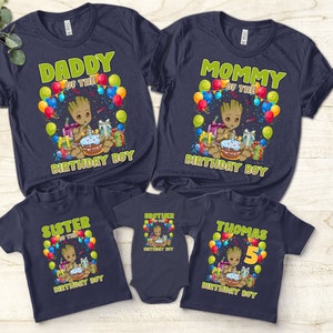 May include: Set of five navy blue t-shirts featuring a cartoon character with a birthday cake and balloons. The shirts say "Daddy of the Birthday Boy", "Mommy of the Birthday Boy", "Sister of the Birthday Boy", "Brother of the Birthday Boy", and "Thomas 5 Birthday Boy".