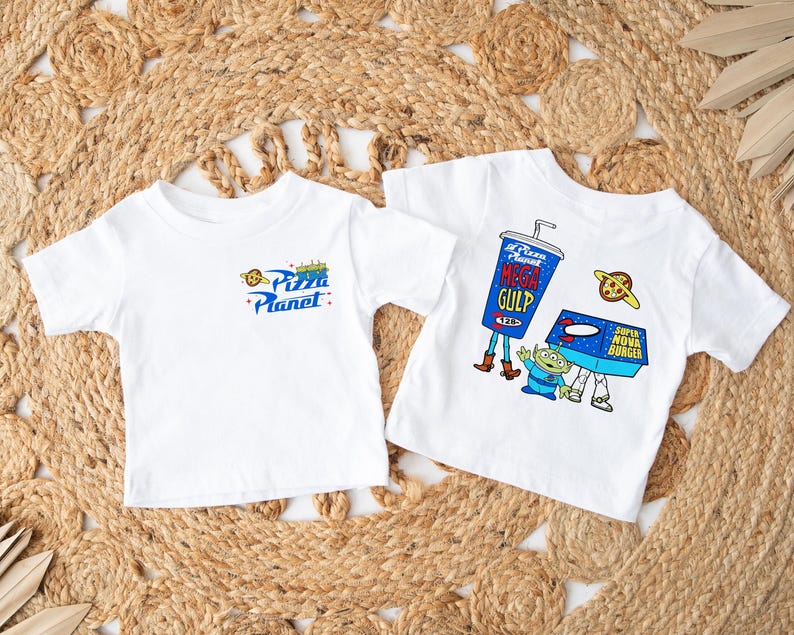 May include: Two white t-shirts with short sleeves. One displays the "Pizza Planet" logo in blue, yellow, and red. The other features a "Mega Gulp" cup, a "Super Nova Burger" box, and an alien character.
