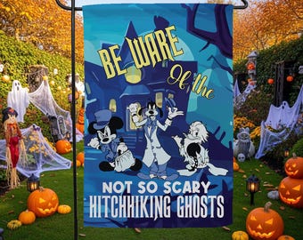 Op de afbeelding: Een rechthoekige tuinvlag met een blauwe achtergrond van een spookhuis en illustraties van Mickey Mouse, Goofy en Donald Duck. De tekst luidt BE WARE of the NOT SO SCARY HITCHHIKING GHOSTS in gele en witte letters.