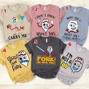 May include: Six different t-shirts featuring a cartoon character from the movie Toy Story. The character is a spork with a face and arms. Each shirt has a different saying on it. The sayings are: Carry Me, I Don't Know About This, Who Am I? What Am I Doing Here?, What The Fork, May The Fork Be With You, I'm Not A Toy.