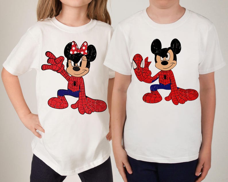 May include: Two white short-sleeved t-shirts featuring graphic prints. The left shirt displays a character with a red polka-dot bow wearing a red and blue spider-web patterned suit. The right shirt shows a character in a similar spider-web suit.