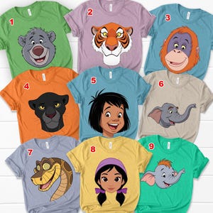 May include: Nine colourful t-shirts featuring characters from The Jungle Book. The shirts are in various colours, including green, purple, orange, and blue. Each shirt has a different character design, such as a bear, tiger, and elephant.