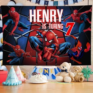 May include: A birthday banner featuring Spider-Man in various action poses. The banner has a red and blue color scheme with the words "HENRY IS TURNING 7" in large white letters. Party hats, a cake, and teddy bears are in the foreground.