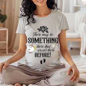 Puede incluir: Una camiseta gris con una rosa negra, texto que dice "Puede que haya algo ahí que no estaba ahí antes!" y una imagen de dibujos animados de una taza de té y un pájaro.