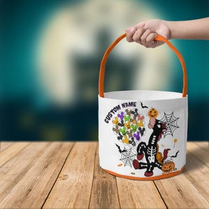 Op de afbeelding: Witte Halloween-emmer met een oranje handvat en rand. De emmer heeft een cartoon skeletpaard met een pompoen, vleermuizen en spinnenwebben. Tekst op de emmer luidt "CUSTOM NAME".