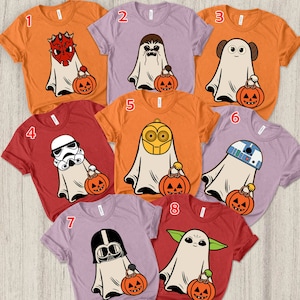 May include: Eight short-sleeved t-shirts in orange, red, and light purple, each featuring a graphic of a character dressed as a ghost holding a jack-o'-lantern. The characters include Darth Maul, Chewbacca, Princess Leia, a Stormtrooper, C-3PO, R2-D2, Darth Vader, and Grogu, numbered one through eight.