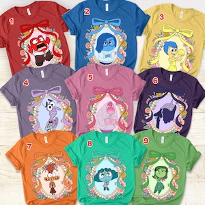 May include: Nine colorful t-shirts featuring characters from the animated movie Inside Out. Each shirt has a different color and character design, framed by a floral and ribbon motif. The shirts are short-sleeved and have a crew neck.