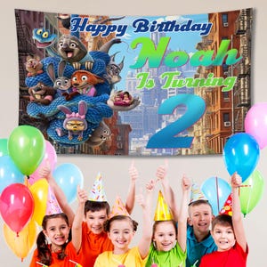 May include: A birthday banner with the text "Happy Birthday Noah Is Turning 2" featuring cartoon characters and a cityscape backdrop. Colourful balloons and children wearing party hats are in the foreground.