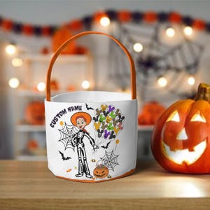 Op de afbeelding: Witte Halloween trick-or-treat tas met een oranje handvat en rand. De tas heeft een stripfiguur in een skeletkostuum, spinnenwebben, vleermuizen en een pompoen. De tekst "CUSTOM NAME" staat op de tas.