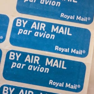 May include: Five blue and white stickers with the text "BY AIR MAIL par avion" and "Royal Mail®" repeated on each sticker.