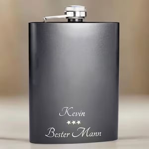 Puede incluir: Frasco de metal negro con tapa plateada y texto grabado que dice "Kevin Mejor Hombre" con cuatro estrellas.