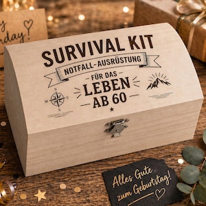 Könnte beinhalten: Eine hellfarbene Holz-Survival-Kit-Box mit dem Text "SURVIVAL KIT" und "NOTFALL-AUSRÜSTUNG" auf dem Deckel. Die Box hat auch den Text "FÜR DAS LEBEN AB 60" und ein Kompass-Design. Eine kleine schwarze Karte mit goldenem Text sagt "Alles Gute zum Geburtstag!"