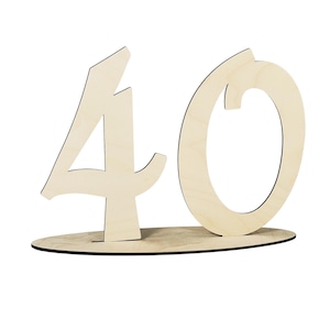 Può includere: Una sagoma in legno di colore chiaro che rappresenta il numero 40, caratterizzata da un carattere stilizzato con angoli acuti sul quattro e uno zero circolare. I numeri sono fissati su una base in legno piatta e ovale, autoportante.