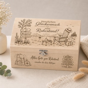 Könnte beinhalten: Eine rechteckige, helle Holzbox mit Klappdeckel und Metallverschluss. Der Deckel zeigt eine Lasergravur mit See, Stuhl und Rucksack sowie den Text "Herzlichen Glückwunsch zum Ruhestand!". Auf der Vorderseite befinden sich ein Rucksack, ein Kompass, der Text "Alles Gute zum Ruhestand wünchen dir deine Kollegen" und Wegweiser.