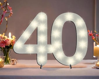 May include: White light-up number 40 made of wood with a white background and small white lights. The number is standing on a white table.