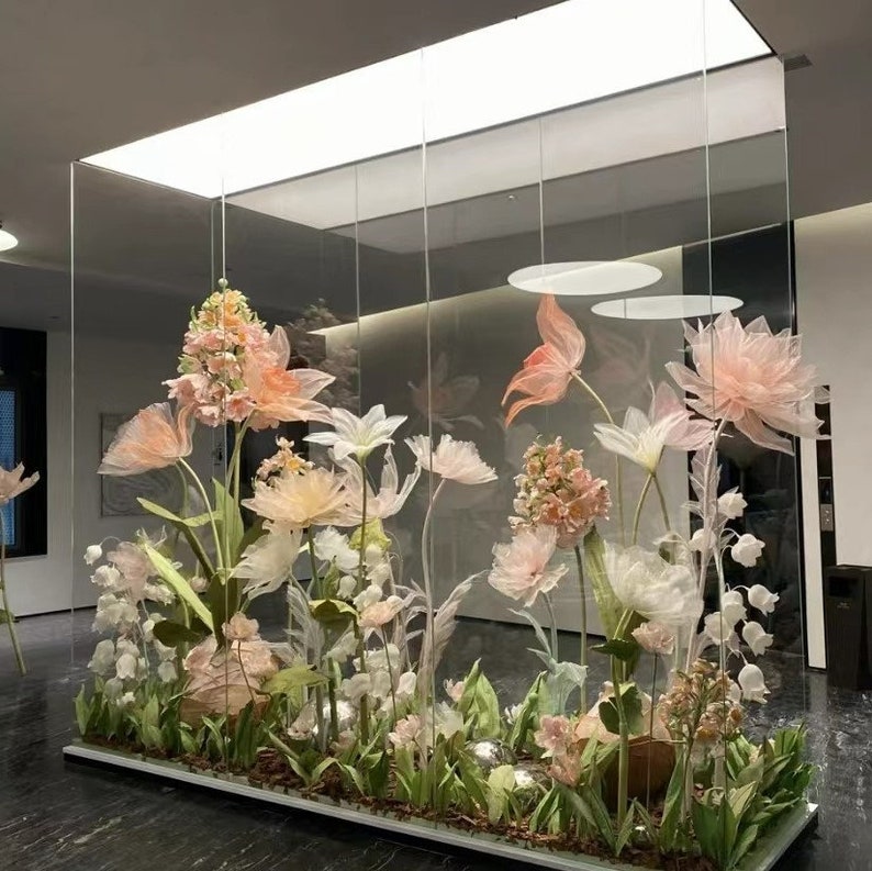 Puede incluir: Una vitrina de cristal llena de delicadas flores de papel en colores pastel. Las flores est&aacute;n dispuestas en una variedad de formas y tama&ntilde;os, creando un ambiente caprichoso y rom&aacute;ntico.