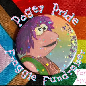 Op de afbeelding: Een ronde button met een stripfiguur met paars haar en een groene en bruine outfit. De button heeft de tekst "Pogey Pride Fraggle Fundraiser for hiv/aids". De achtergrond is een regenboogvlag.