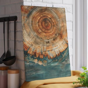 May include: Rectangular wooden cutting board with a detailed cross-section design. The board features concentric rings in shades of brown and orange, transitioning to a teal blue at the bottom. The board is displayed near a window.