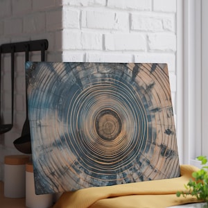 May include: A rectangular wooden cutting board with a circular wood grain pattern. The board features concentric rings in shades of blue and tan, creating a visual focal point. The board is displayed near a window and kitchen utensils.