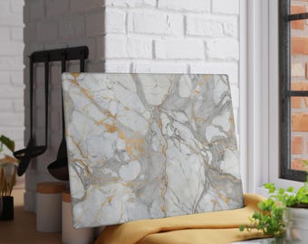 Könnte beinhalten: Ein rechteckiges Schneidebrett aus Marmor mit einem weißen, grauen und goldenen Adernmuster. Das Brett liegt auf einem gelben Tuch vor einer weißen Backsteinmauer. Küchenutensilien hängen an der Wand dahinter.