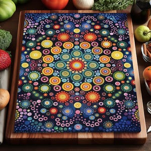 Puede incluir: Tabla de cortar rectangular con un colorido diseño de mandala. El diseño presenta círculos concéntricos en tonos de azul, naranja, amarillo y verde sobre un fondo azul oscuro. La tabla es de madera y está rodeada de productos frescos.