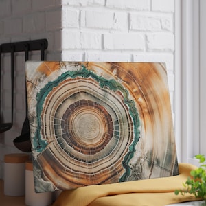 May include: A rectangular cutting board with a detailed cross-section of a tree trunk. The design features concentric rings in shades of brown, beige, and teal. The board is placed on a yellow cloth near a window.