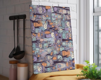 May include: A rectangular cutting board with a whimsical, cartoon-style illustration. The design features numerous stylized figures in shades of purple, blue, orange, and beige against a dark purple background. The board is propped up near a window.