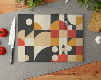 May include: Rectangular cutting board with a geometric design in black, beige, red, and yellow. A stainless steel knife with a black handle is to the left of the board. Red tomatoes and bread are also visible.