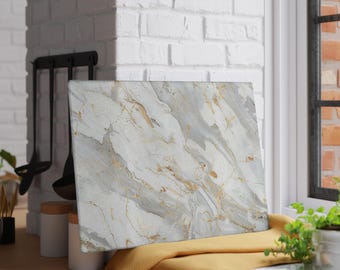 May include: A rectangular cutting board with a marble design. The board features a white base with gray and gold veining. It rests on a yellow cloth near a window and a white brick wall.