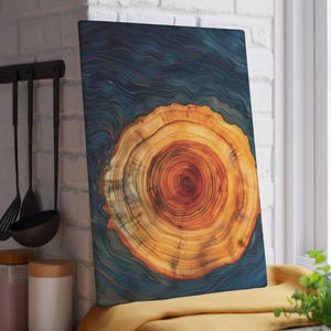 May include: A rectangular cutting board with a wood grain design. The center features a detailed cross-section of a tree trunk, showcasing concentric rings in shades of orange and brown against a dark blue background. The board is displayed in a kitchen setting.
