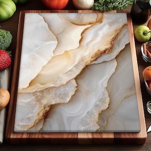 Op de afbeelding: Een rechthoekige snijplank met een wit en bruin marmerontwerp. De plank staat op een houten dienblad. Het marmerpatroon heeft een natuurlijk, vloeiend uiterlijk, met strepen in bruine en crèmekleuren. De plank is omgeven door verse producten.
