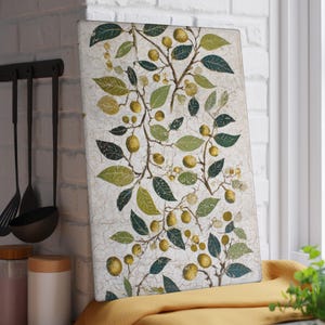 May include: Rectangular decorative cutting board with a botanical design. The artwork features branches with green leaves and yellow fruit against a textured, off-white background. The board is displayed near a window and kitchen utensils.