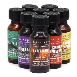 May include: A selection of small, dark glass bottles with black lids, each displaying a different fragrance name. The labels feature the "lifescapes" logo and scents such as "Cinnamon Spiced Apple" and "Vanilla Cupcake". Each bottle contains 55 ml of fragrance warming oil.