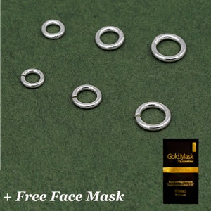 May include: Several silver jump rings of different sizes are arranged on a dark green background. A small black and gold face mask packet is in the lower right. The text "+ Free Face Mask" is at the bottom.