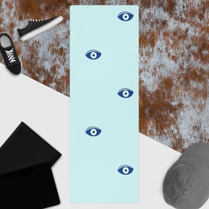 May include: A light blue yoga mat with a repeating pattern of blue evil eyes.