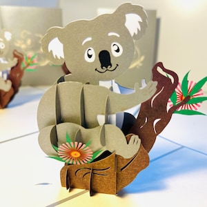 Cartão comemorativo pop-up 3D com coala australiano e flores de nogueira-da-jamaica - Lembrança de origami feita à mão em Sydney - Compre online https://origamipopcards.com/