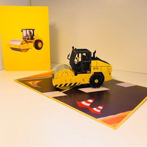 Caminhão rolo compressor constrói uma cidade perfeita para trabalhadores da construção civil e crianças. Cartão comemorativo pop-up 3D. Cartões pop-up de origami. https://origamipopcards.com/
