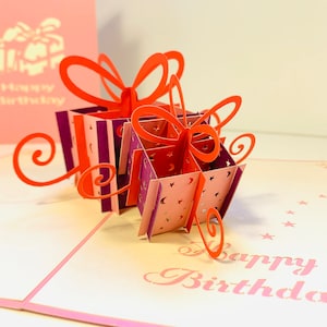 Cartão de felicitações pop-up feito à mão, em formato de coração, rosa e vermelho, com dois presentes de feliz aniversário. Compre online https://origamipopcards.com/