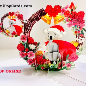 Tarjeta de felicitación 3D emergente con koala de Papá Noel y corona de flores nativas australianas, hecha a mano, tienda en línea https://origamipopcards.com/ Love