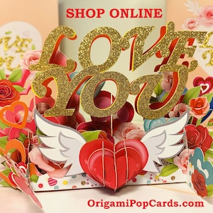 May include: A 3D pop-up card with a gold glitter "LOVE YOU" message, surrounded by red roses and hearts. The card is open and the message is raised. The card has white wings on either side of the message. The card is on a white background with the website "OrigamiPopCards.com" printed at the bottom.