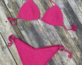 May include: A crocheted bikini set in a deep pink color. The top is a triangle style with adjustable straps and the bottom is a high-waisted, cheeky style.