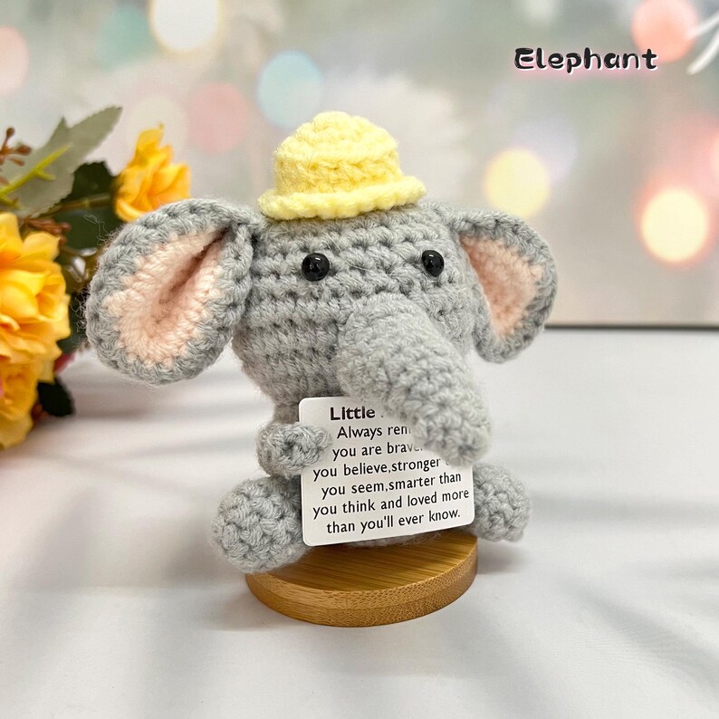May include: A gray crocheted elephant wearing a yellow hat holds a card with the text "Little Always remember you are brave you believe, stronger you seem, smarter than you think and loved more than you'll ever know."