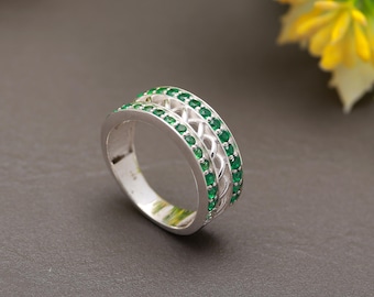 Könnte beinhalten: Ein silberner Ring mit einem keltischen Knotendesign und zwei Reihen grüner Edelsteine.
