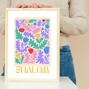 May include: A framed print featuring a colourful floral design and the word "SHALOM" in gold lettering.