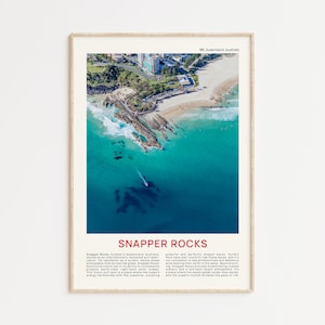May include: An aerial photograph of Snapper Rocks, a popular surf spot in Queensland, Australia. The image shows turquoise water crashing against rocky shores and a sandy beach. The text "Snapper Rocks" is displayed in red at the bottom of the image.